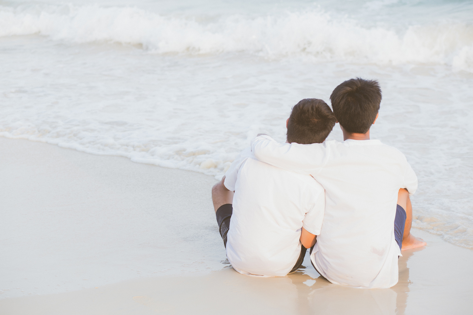 LGBT Couple Sitting and Embracing by the Sea