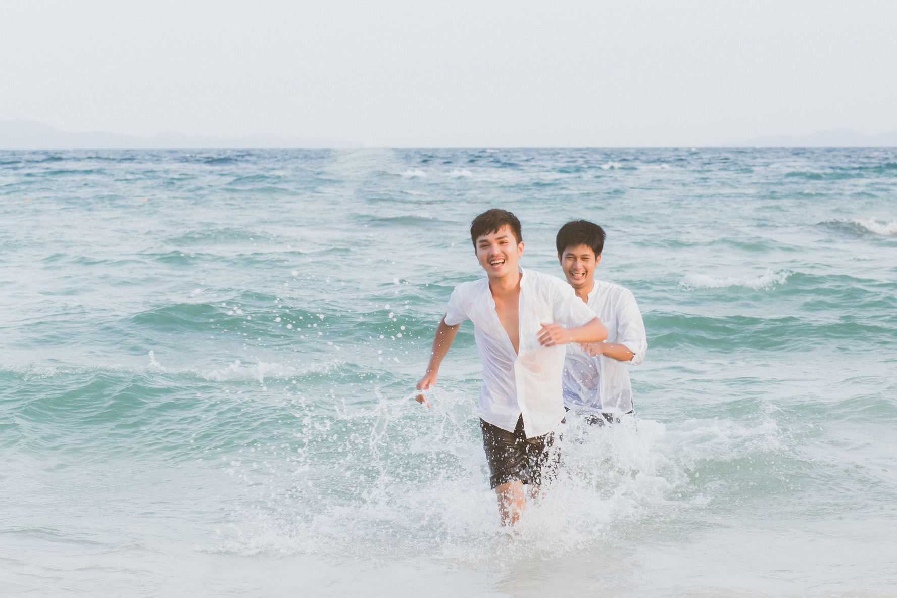 Asian Gay Couple Running on the Water at the Beach 