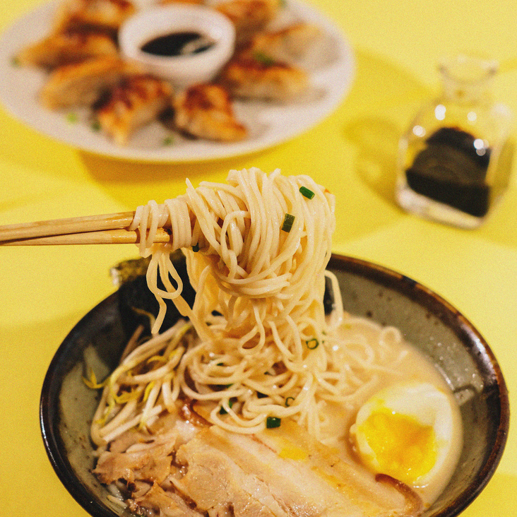 Bowl of Ramen with Plate of Gyoza on Background